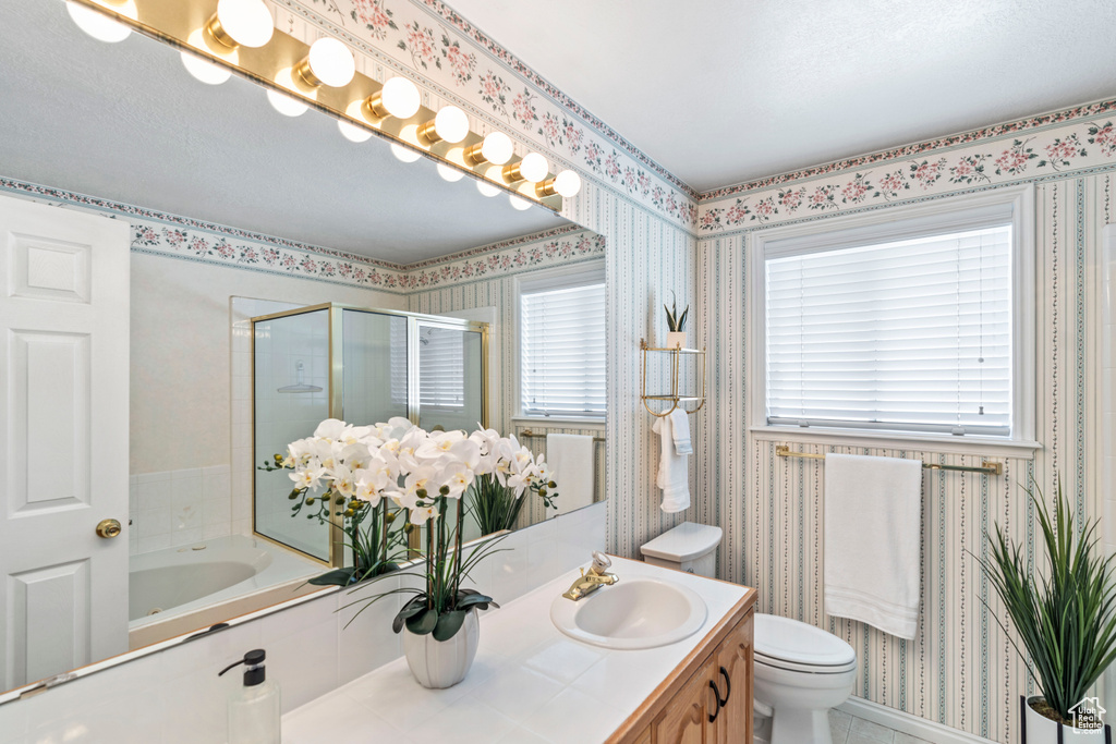 Bathroom featuring a stall shower, wallpapered walls, toilet, and vanity