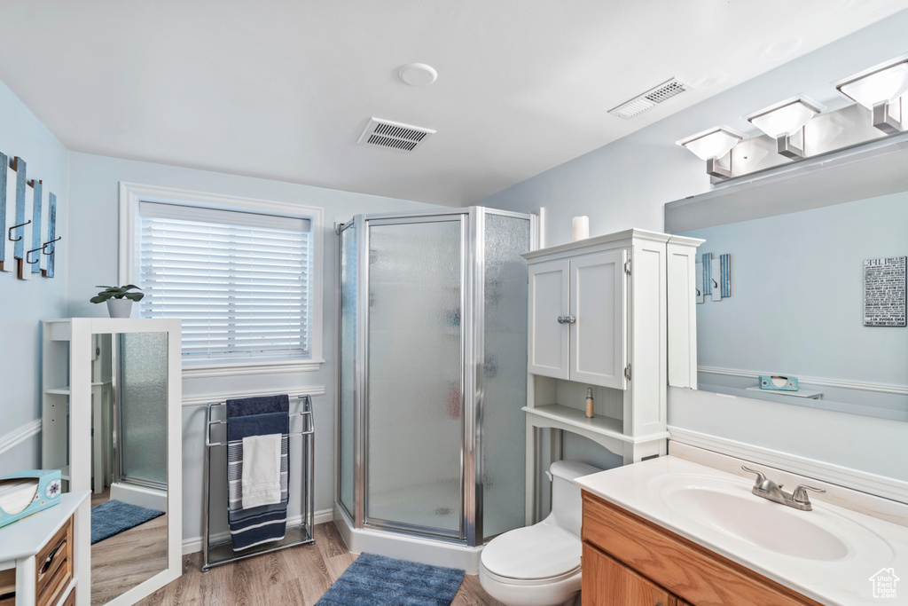 Full bath with wood finished floors, a shower stall, vanity, and toilet