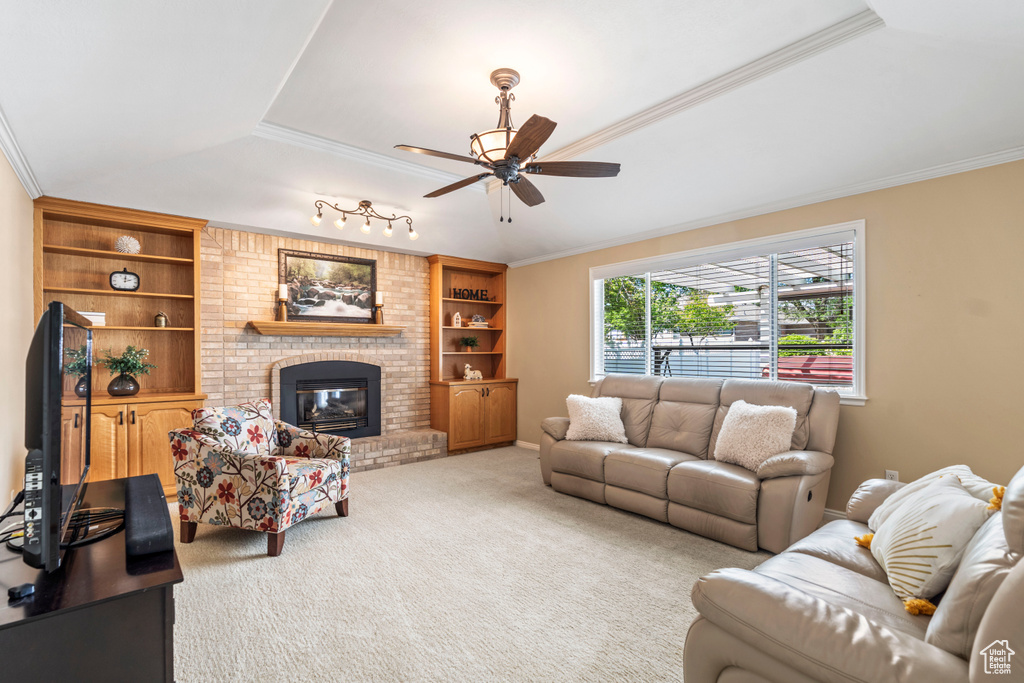 Living area with a ceiling fan, carpet, crown molding, a fireplace, and built in features
