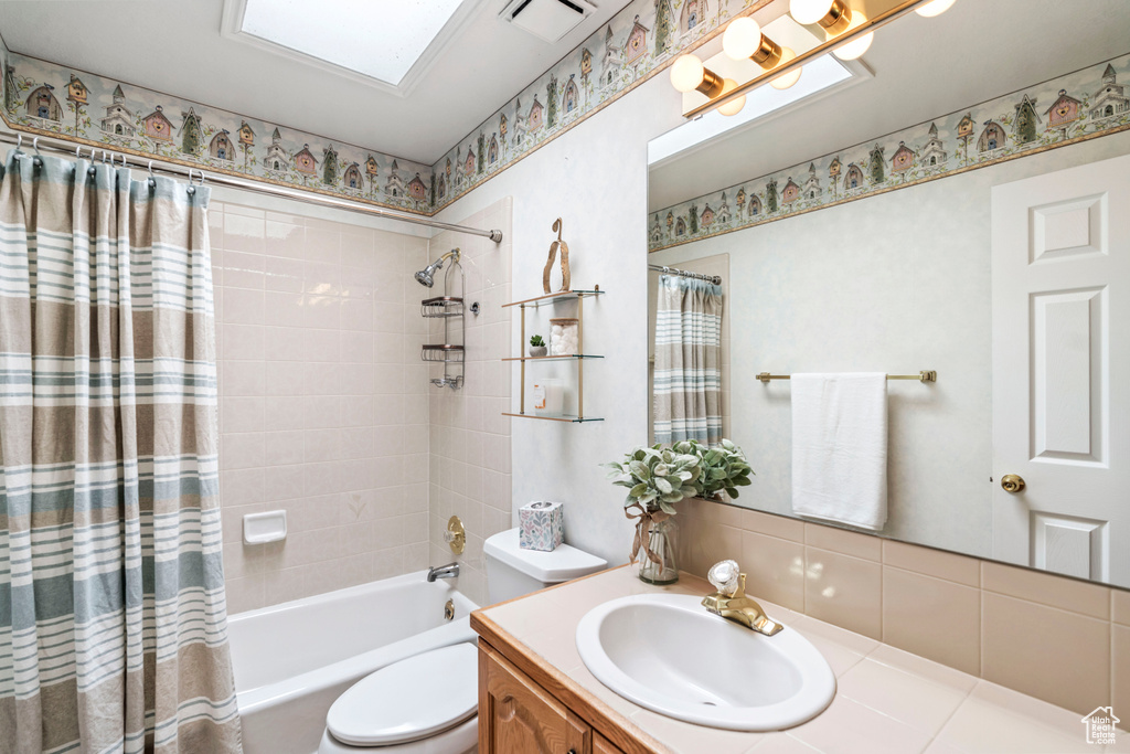 Bathroom with toilet, shower / bath combo, and vanity