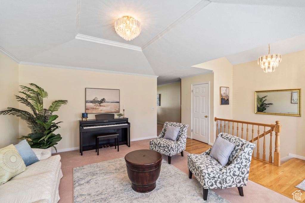 Living area with a chandelier, an upstairs landing, crown molding, baseboards, and wood finished floors
