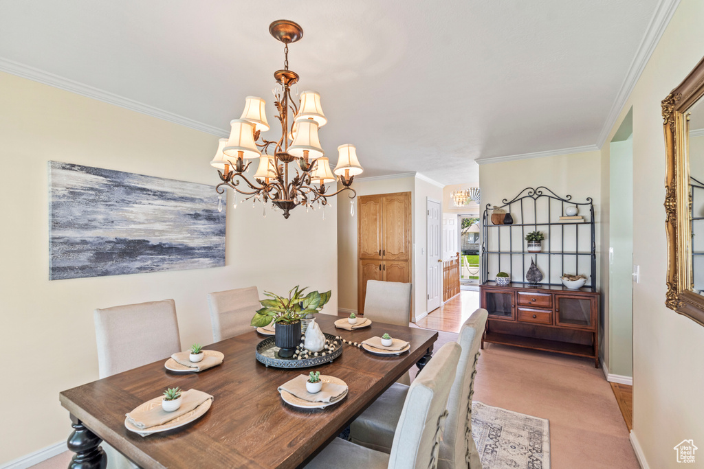 Dining area featuring a chandelier, ornamental molding, baseboards, and light colored carpet