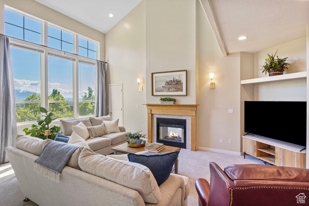 Living area with carpet floors, high vaulted ceiling, a fireplace, baseboards, and recessed lighting