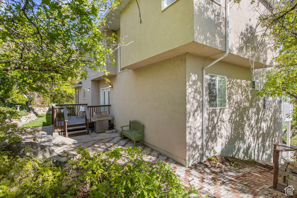 View of property exterior with a patio, a wooden deck, and stucco siding