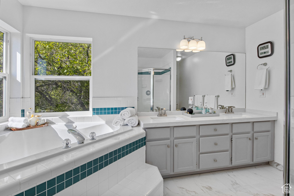 Bathroom featuring a stall shower, plenty of natural light, a bath, and double vanity