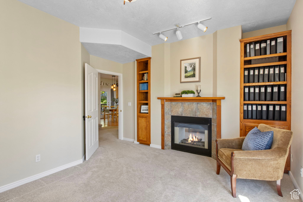 Sitting room with carpet flooring, a tile fireplace, baseboards, and a textured ceiling