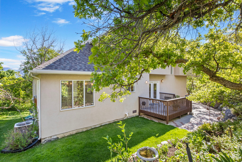 Back of house featuring roof with shingles, a wooden deck, a yard, stucco siding, and french doors