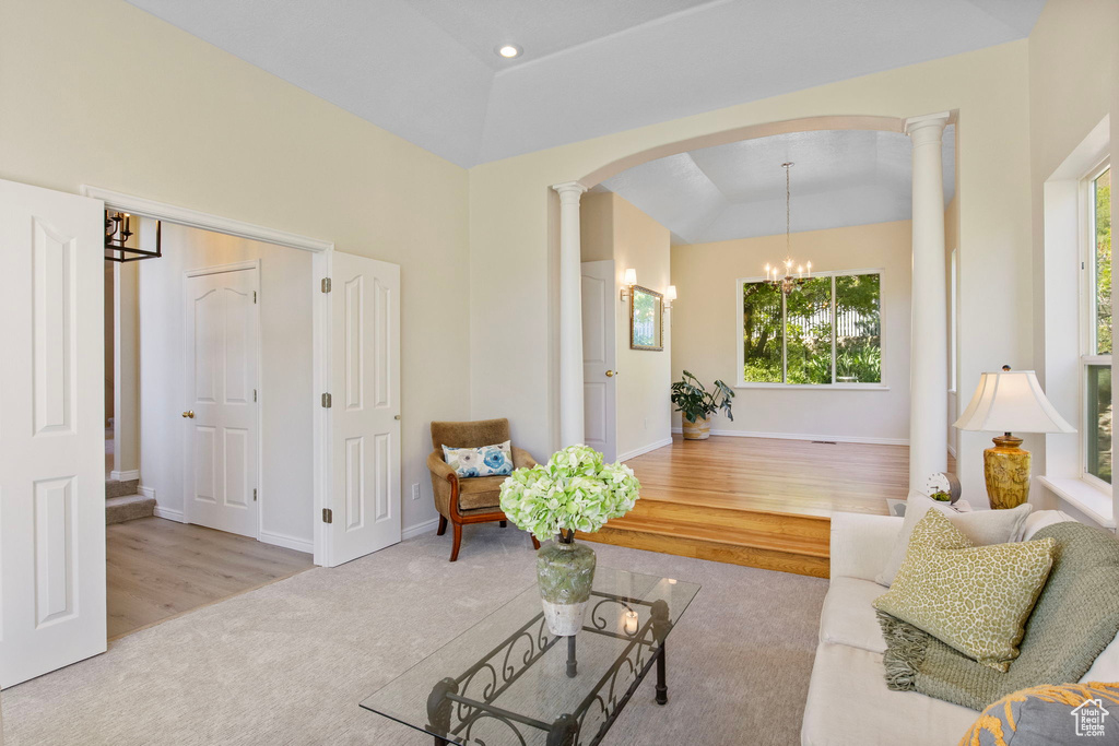 Carpeted living room featuring arched walkways, plenty of natural light, ornate columns, and a raised ceiling