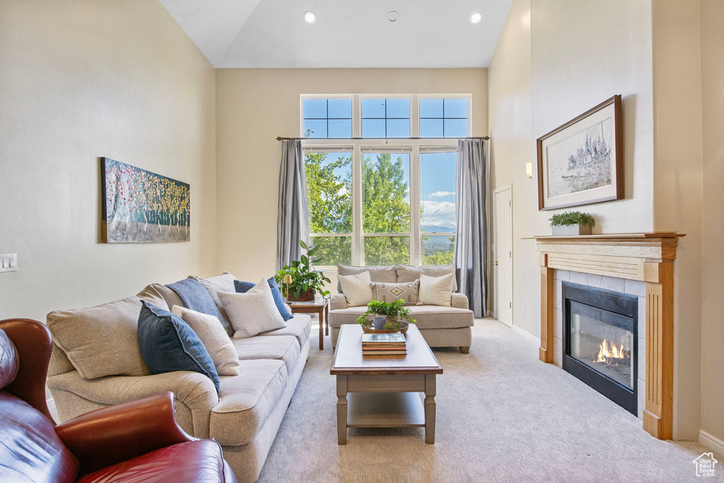 Living room featuring a tiled fireplace, carpet floors, baseboards, high vaulted ceiling, and recessed lighting