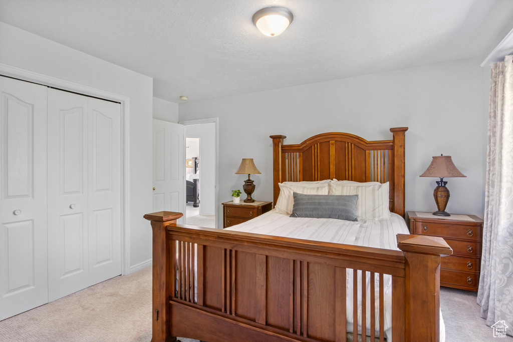 Bedroom with light colored carpet and a closet