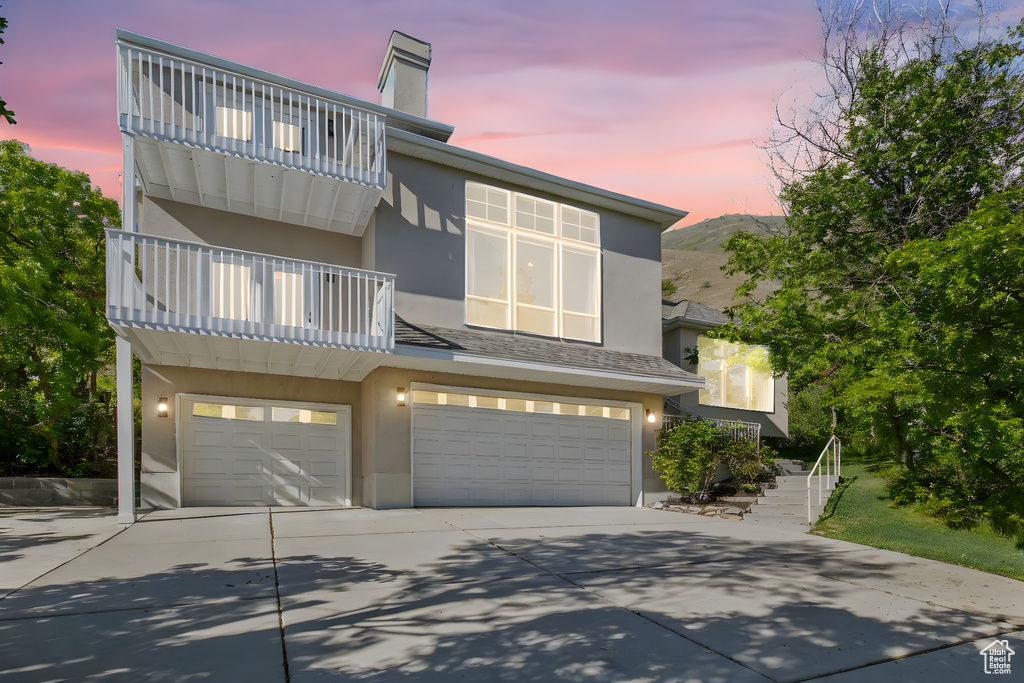 Townhome / multi-family property with a balcony, stucco siding, a garage, and driveway