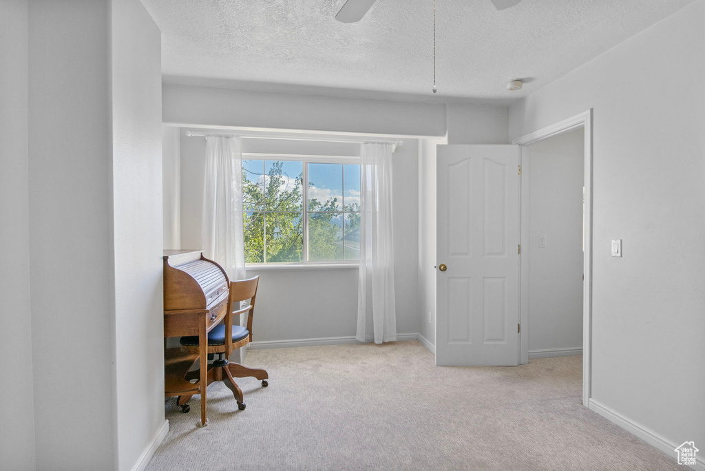 Home office with a textured ceiling, carpet floors, baseboards, and ceiling fan