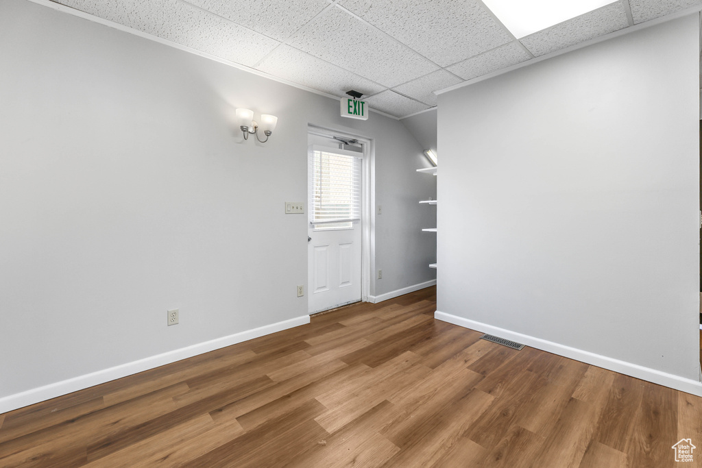 Unfurnished room with baseboards, a paneled ceiling, wood finished floors, and visible vents