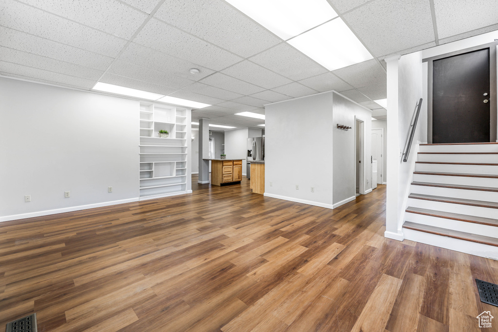 Basement with dark wood-style floors, baseboards, visible vents, and built in shelves
