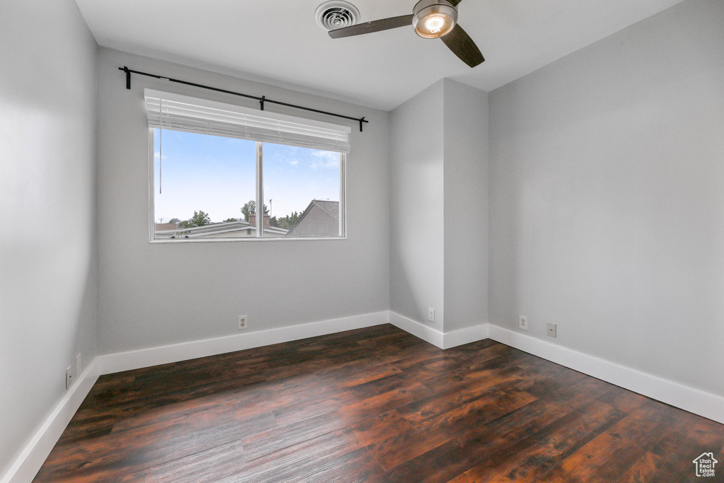 Spare room with baseboards, a ceiling fan, dark wood finished floors, and visible vents