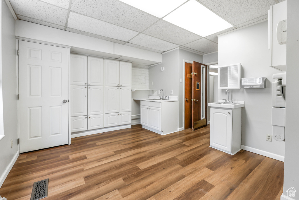 Interior space featuring visible vents, a drop ceiling, and white cabinets