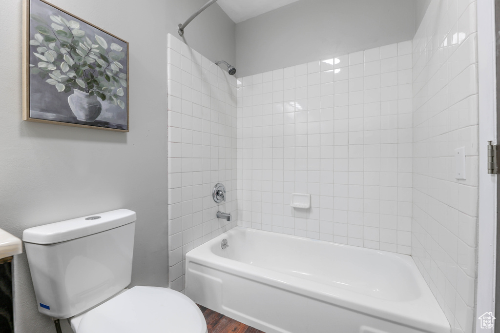 Bathroom with toilet, wood finished floors, and shower / bathing tub combination