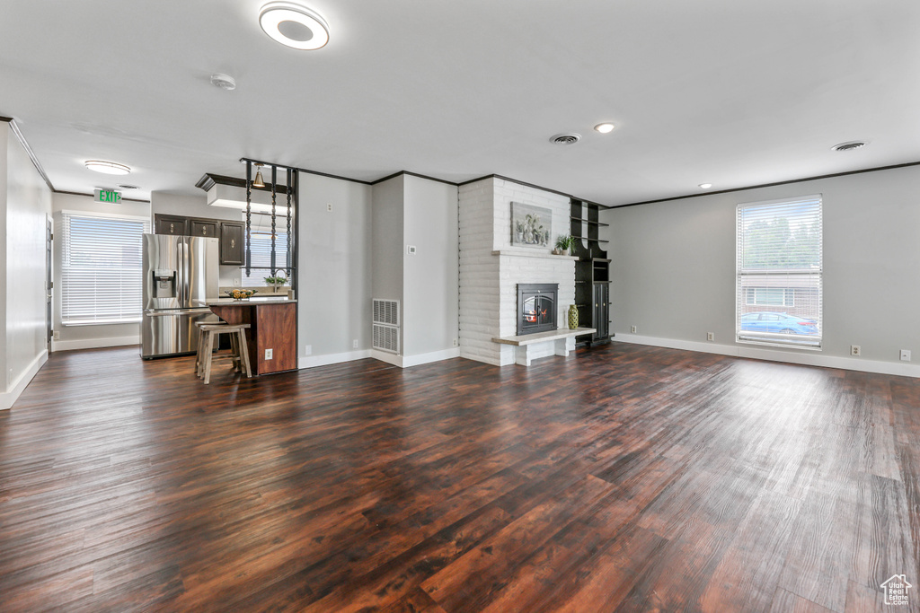 Unfurnished living room with baseboards and dark wood-type flooring