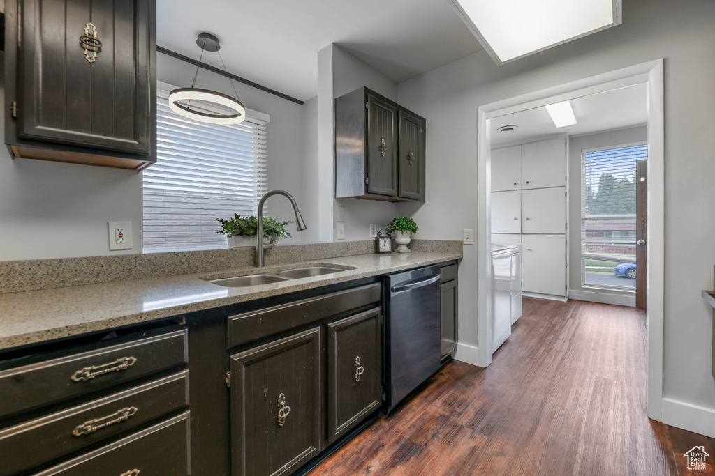 Kitchen featuring dark wood-type flooring, a sink, baseboards, and dishwasher