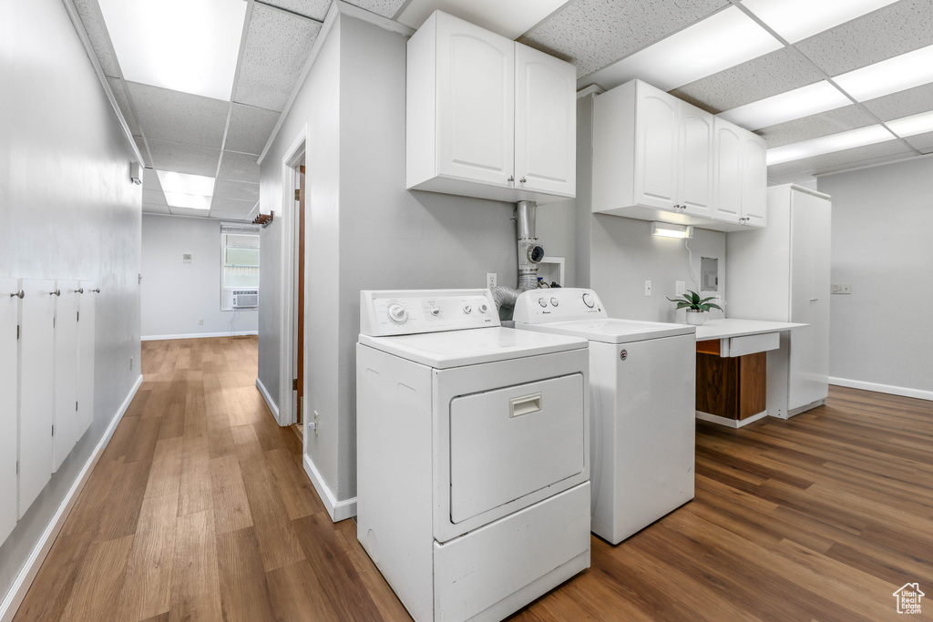 Laundry area featuring baseboards, washer and clothes dryer, cabinet space, and wood finished floors