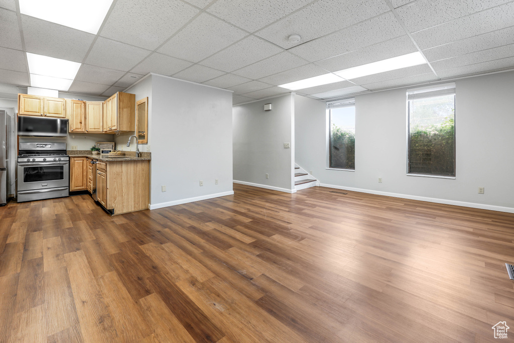 Interior space with open floor plan, a drop ceiling, a sink, and gas range