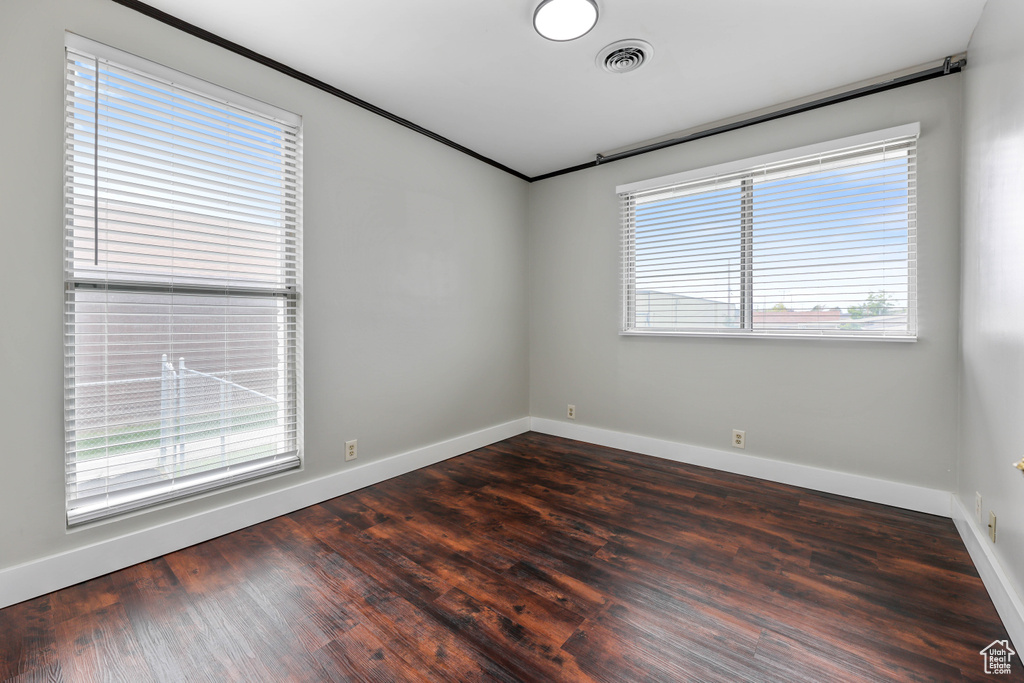 Empty room with visible vents, baseboards, and dark wood finished floors