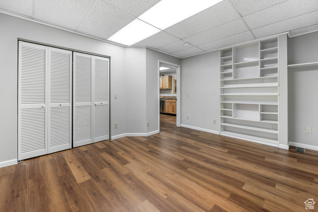 Unfurnished bedroom with visible vents, a paneled ceiling, wood finished floors, baseboards, and a closet