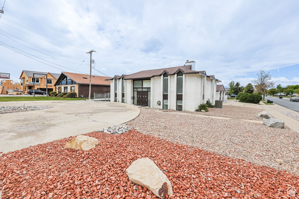 View of building exterior featuring a garage, central air condition unit, and concrete driveway