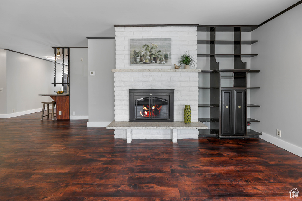 Living area with baseboards, a brick fireplace, and wood finished floors