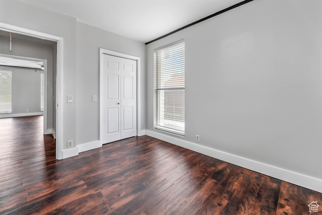 Unfurnished bedroom with baseboards, dark wood finished floors, and multiple windows