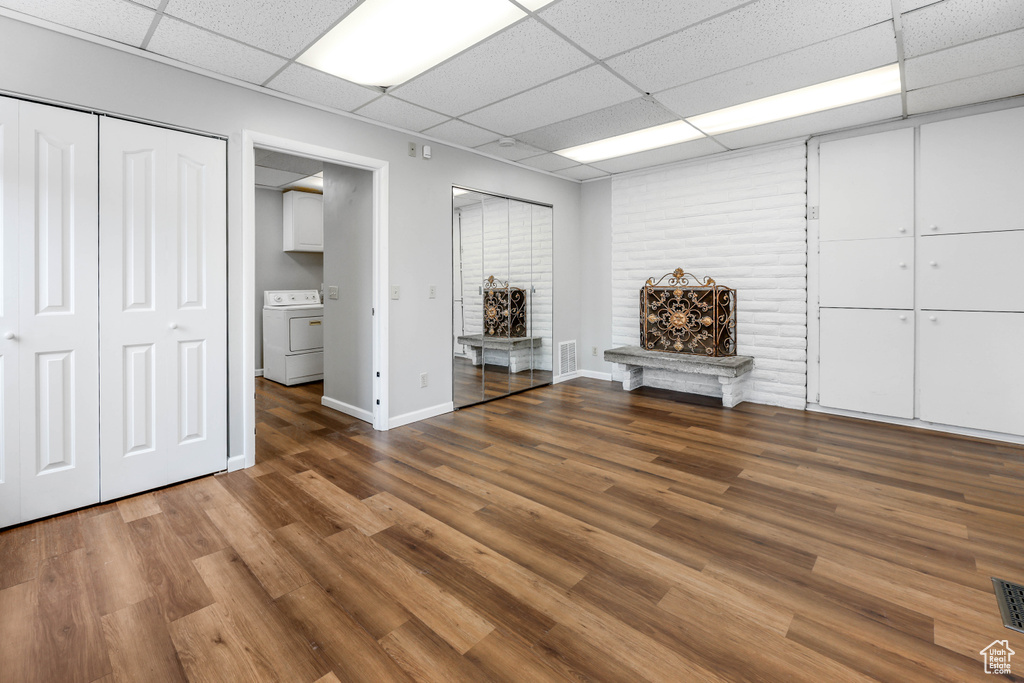 Below grade area featuring visible vents, wood finished floors, baseboards, washer / dryer, and a drop ceiling