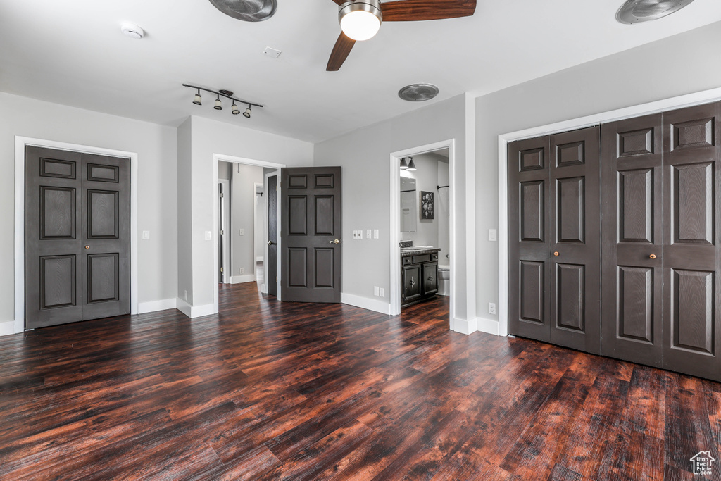 Unfurnished bedroom with baseboards, a ceiling fan, ensuite bath, and wood finished floors