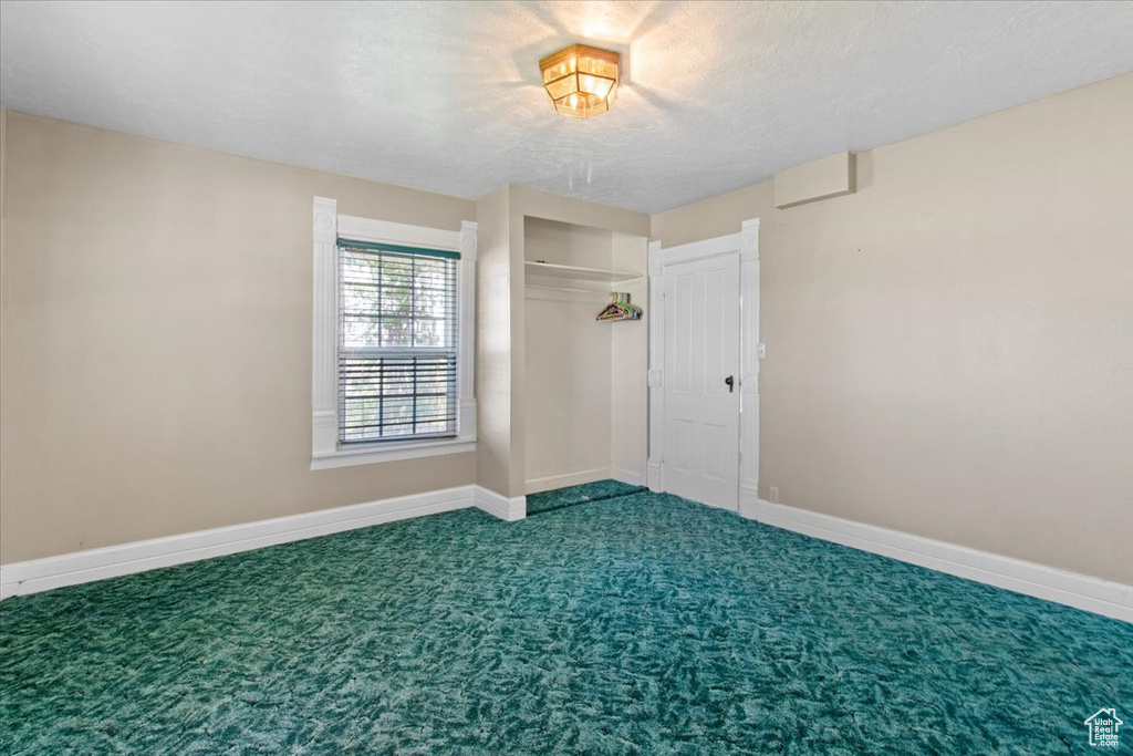 Carpeted empty room with baseboards and a textured ceiling