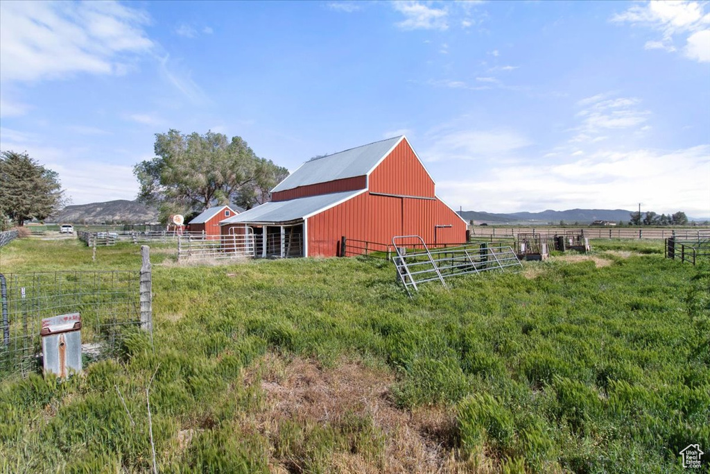 View of yard with a barn, fence, a view of countryside, and an outbuilding