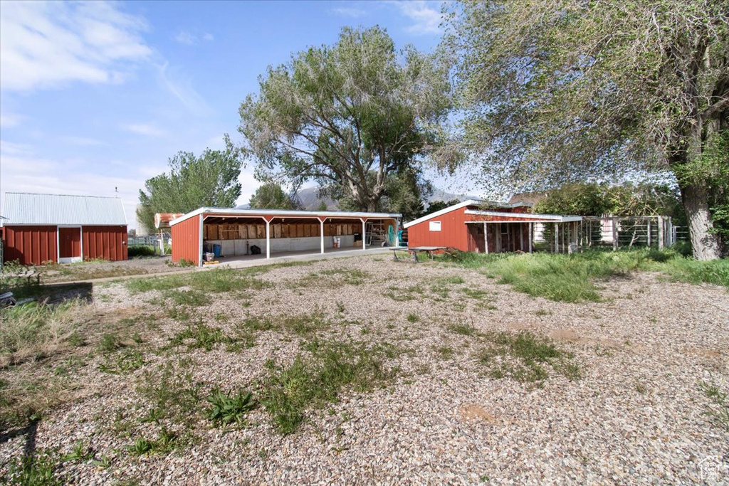 Back of house featuring a pole building and an outbuilding