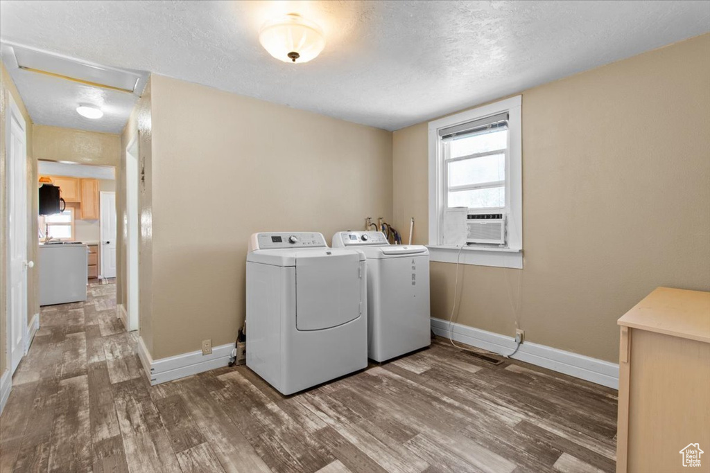 Washroom featuring separate washer and dryer, wood finished floors, a textured ceiling, baseboards, and cooling unit