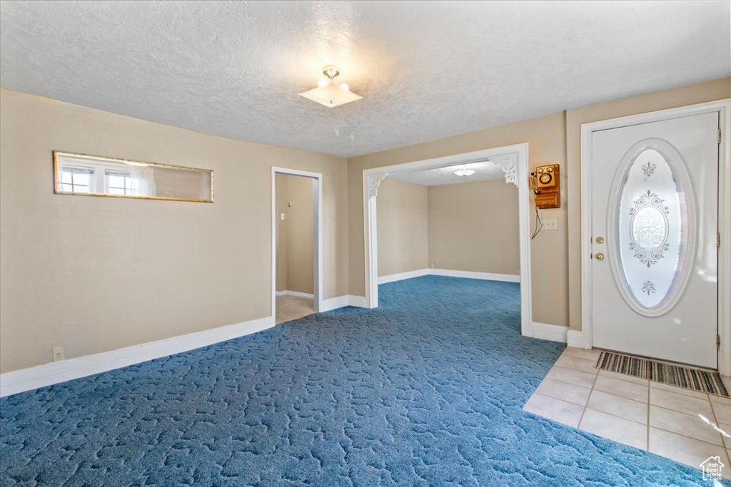 Carpeted foyer featuring baseboards and a textured ceiling