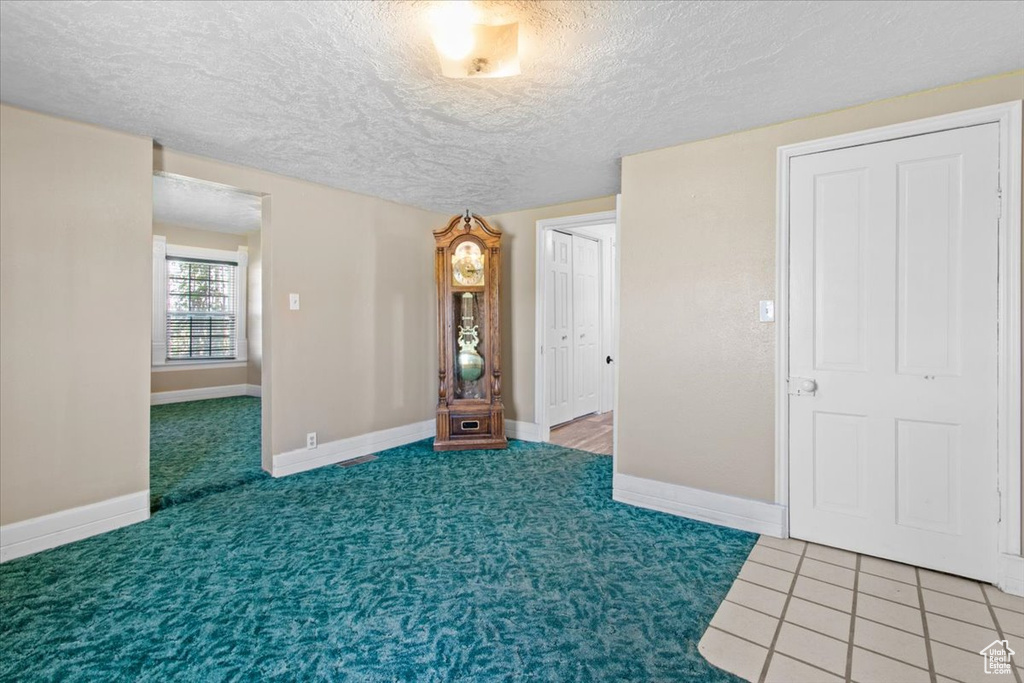 Carpeted empty room featuring a textured ceiling and baseboards