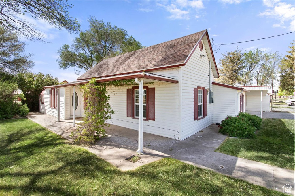 View of side of home with a lawn and roof with shingles