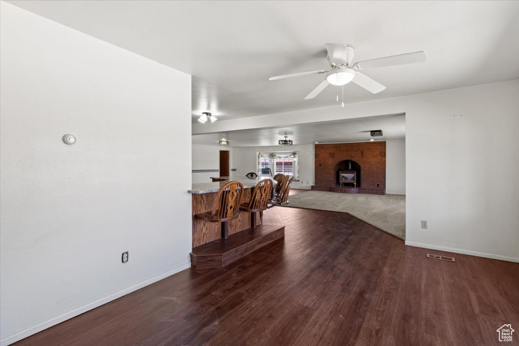 Living room with baseboards, wood finished floors, a ceiling fan, and a fireplace