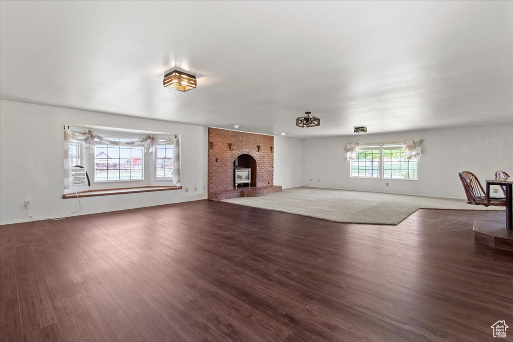Unfurnished living room featuring wood finished floors and a brick fireplace