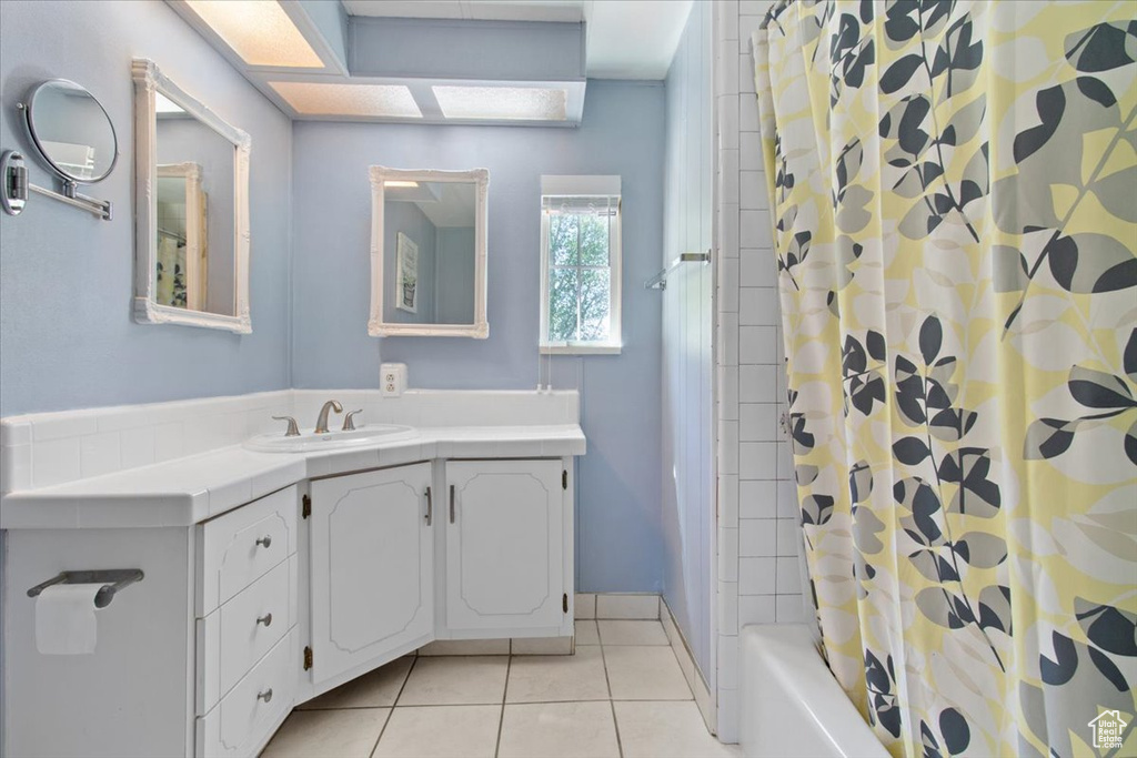 Bathroom featuring tile patterned floors, vanity, and shower / bath combination with curtain