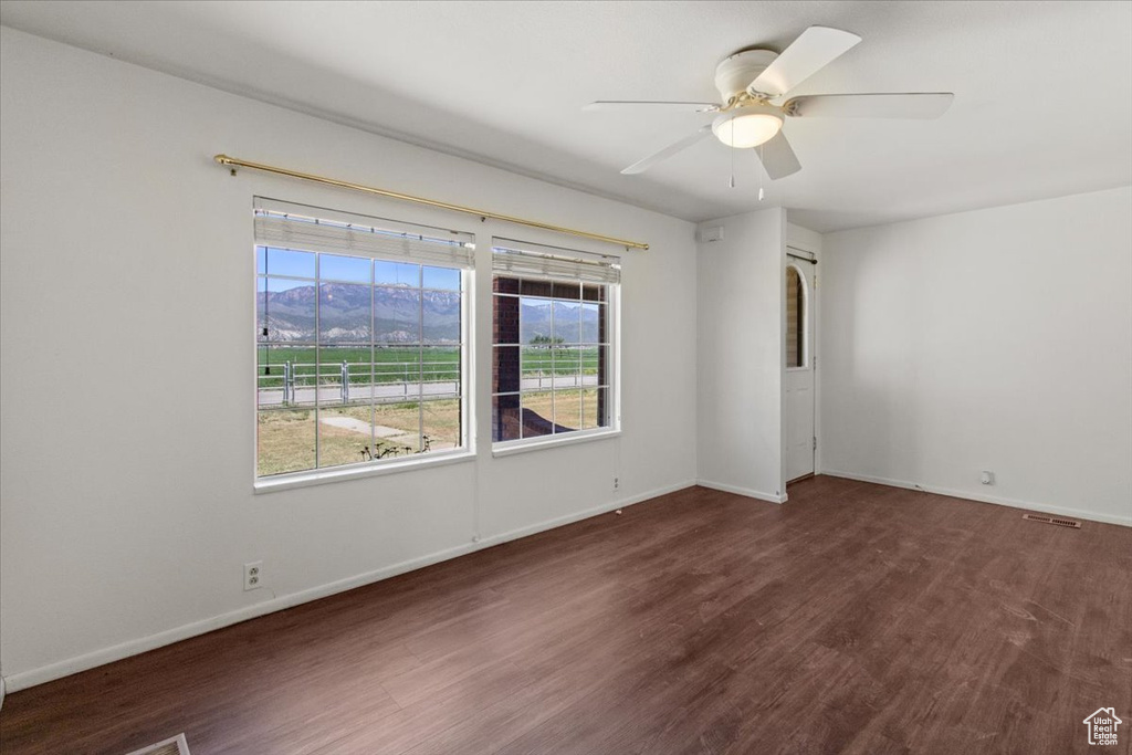 Spare room with wood finished floors, a mountain view, a ceiling fan, and baseboards
