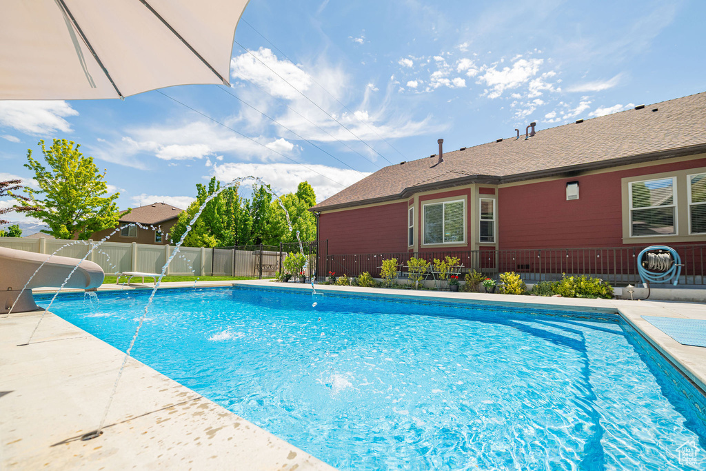 View of swimming pool featuring fence, a water slide, and a patio