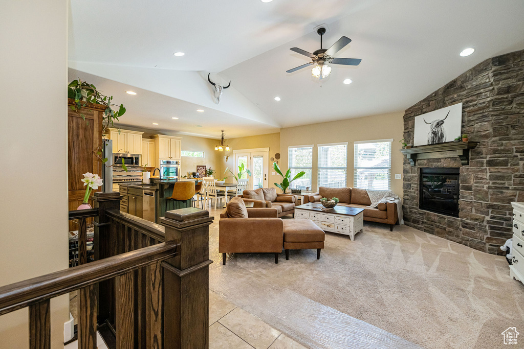 Living area with lofted ceiling, recessed lighting, ceiling fan, a stone fireplace, and light tile patterned floors