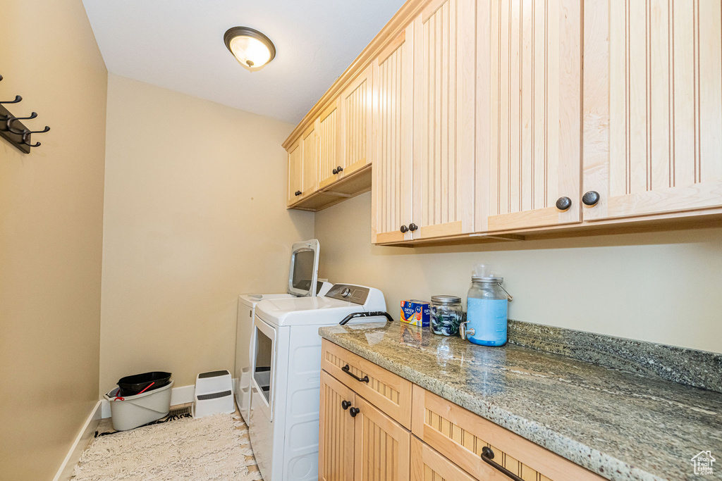 Clothes washing area featuring cabinet space, washer and clothes dryer, and baseboards