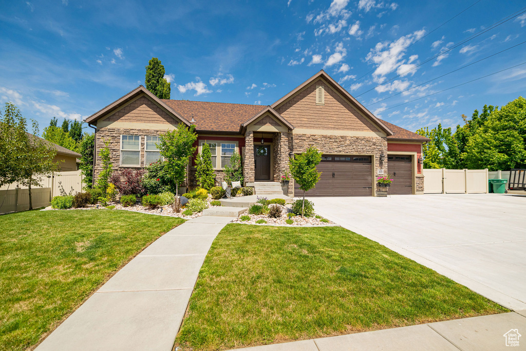 Craftsman-style home featuring stone siding, a garage, and concrete driveway