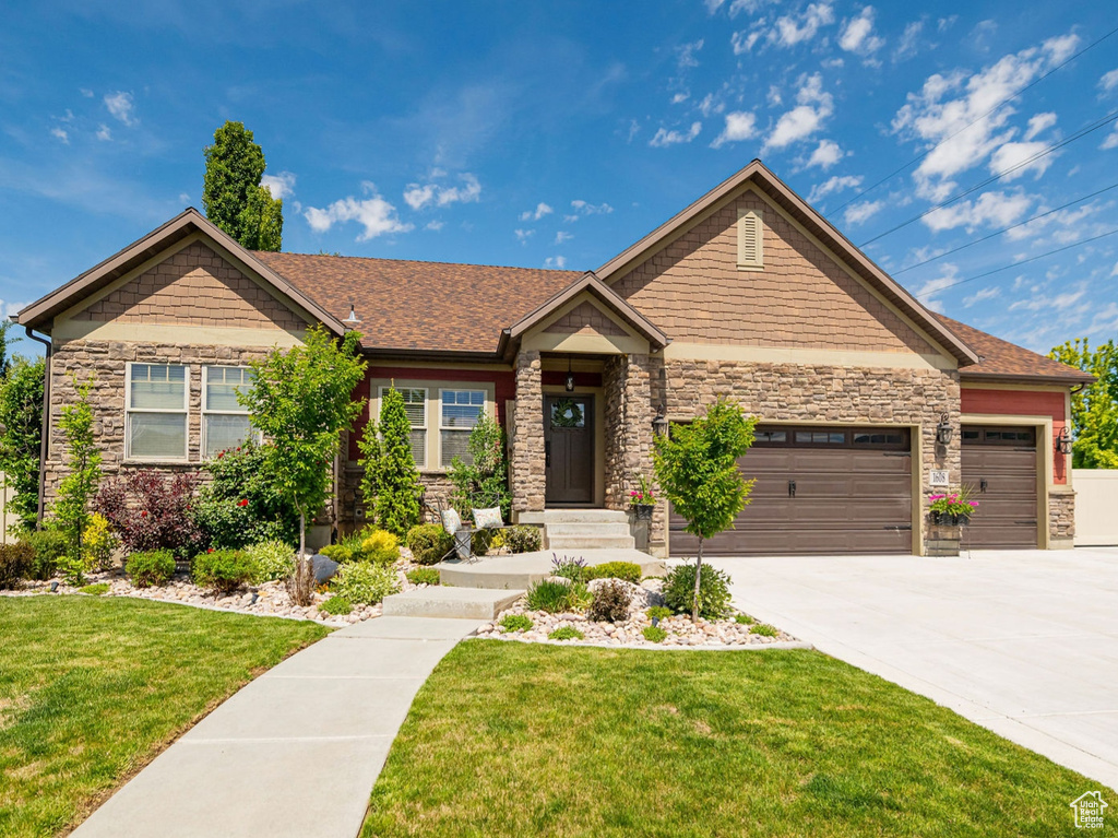 Craftsman-style home featuring stone siding, a garage, and concrete driveway
