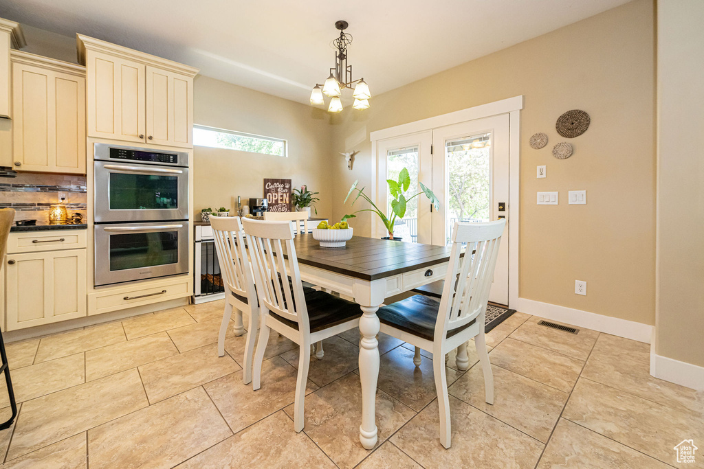 Dining area featuring light tile patterned floors, baseboards, and a chandelier