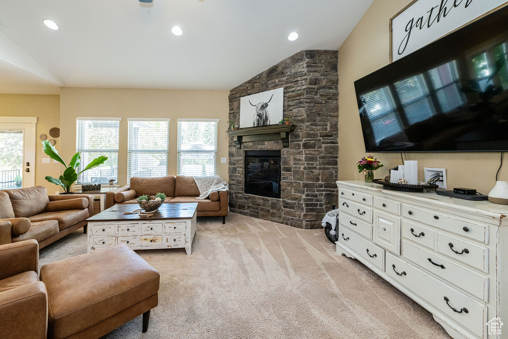 Living room featuring lofted ceiling, light carpet, a stone fireplace, and recessed lighting